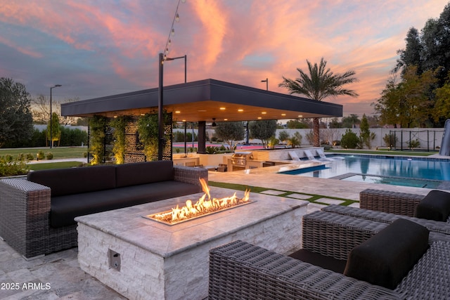 pool at dusk with a patio area and an outdoor living space with a fire pit