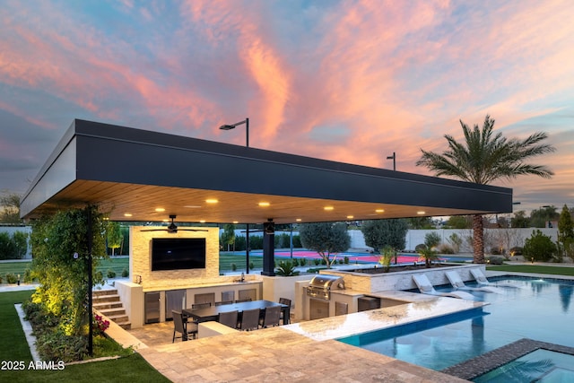 view of pool with an outdoor bar, ceiling fan, a patio area, area for grilling, and exterior kitchen