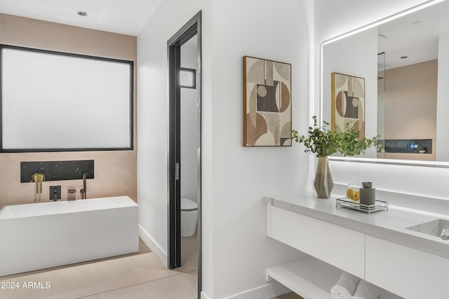 bathroom with a washtub, toilet, and vanity