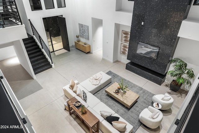 living room featuring a fireplace, a towering ceiling, and light tile patterned floors