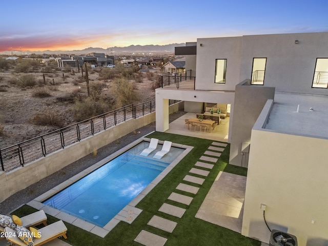 pool at dusk with a mountain view and a patio