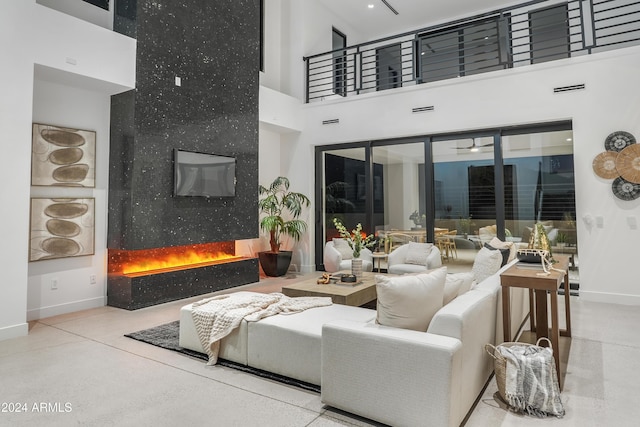 living room featuring ceiling fan, a high end fireplace, and a high ceiling