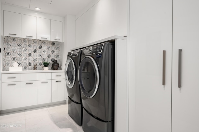 washroom with light tile patterned floors, cabinets, and washer and dryer