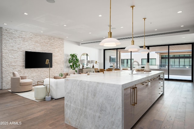 kitchen featuring a large island, sink, decorative light fixtures, and plenty of natural light