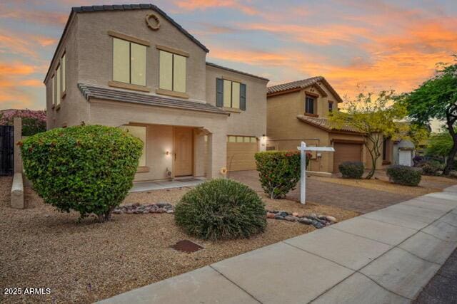 view of front of property with a garage, stucco siding, driveway, and a tiled roof