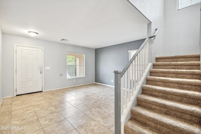 entryway featuring stairs, light tile patterned floors, and baseboards