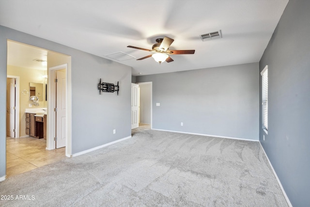 unfurnished room featuring a ceiling fan, light colored carpet, baseboards, and light tile patterned floors