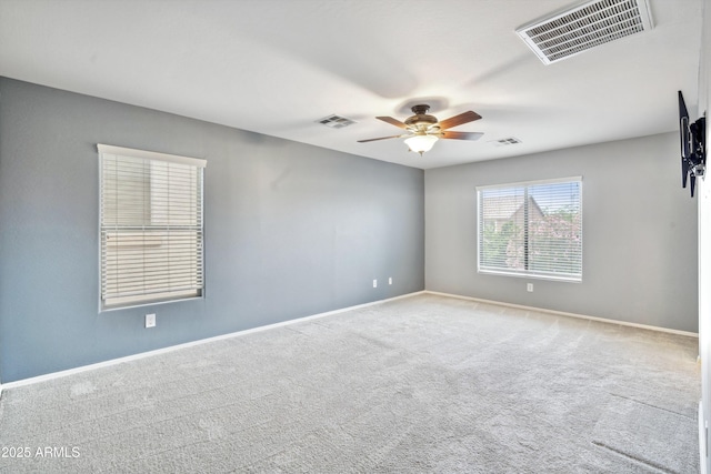 carpeted spare room with a ceiling fan and baseboards