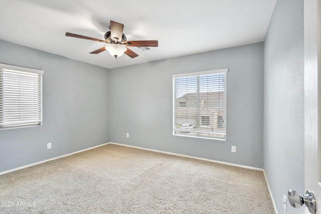 carpeted spare room featuring a ceiling fan and baseboards