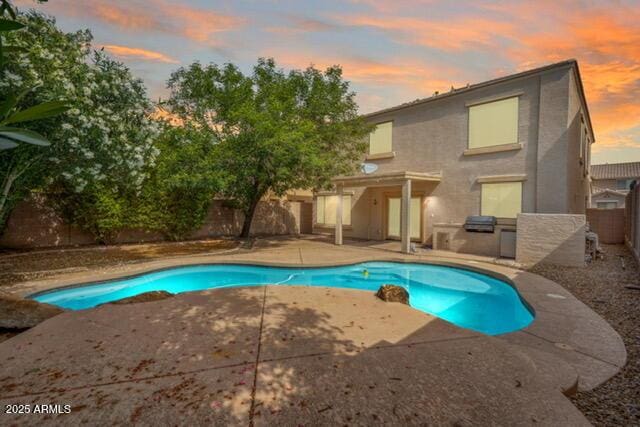 view of swimming pool featuring a patio area, a fenced backyard, and an outdoor kitchen