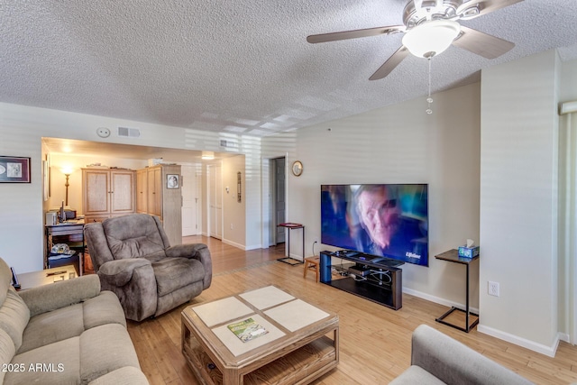 living room with a ceiling fan, a textured ceiling, visible vents, and wood finished floors