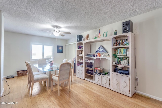 dining space featuring baseboards, ceiling fan, light wood-style flooring, and a textured ceiling
