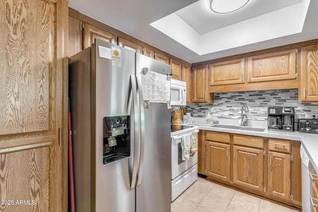 kitchen featuring white appliances, light countertops, tasteful backsplash, a sink, and light tile patterned floors