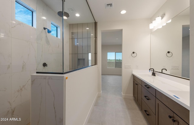 bathroom featuring tiled shower, vanity, and tile patterned flooring