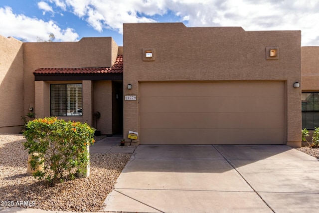 adobe home with a tiled roof, an attached garage, driveway, and stucco siding