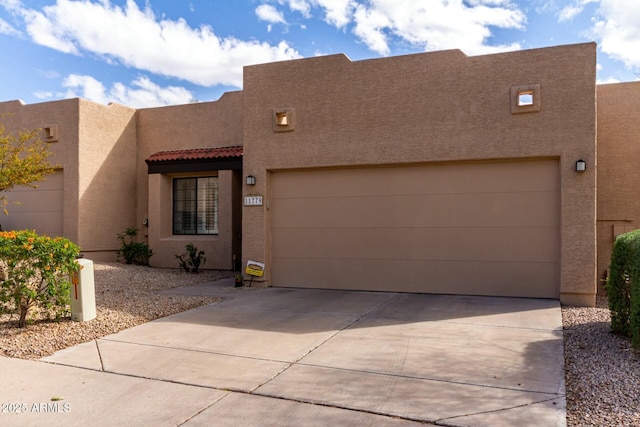 adobe home with stucco siding, a garage, concrete driveway, and a tile roof