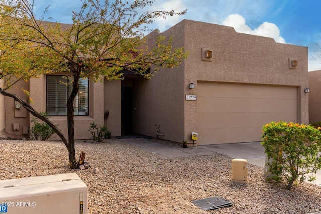 pueblo-style home featuring concrete driveway, a garage, and stucco siding