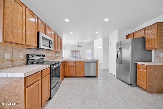 kitchen featuring kitchen peninsula, appliances with stainless steel finishes, decorative backsplash, and sink