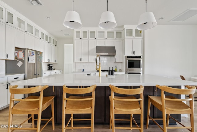 kitchen with a center island with sink, pendant lighting, and range hood