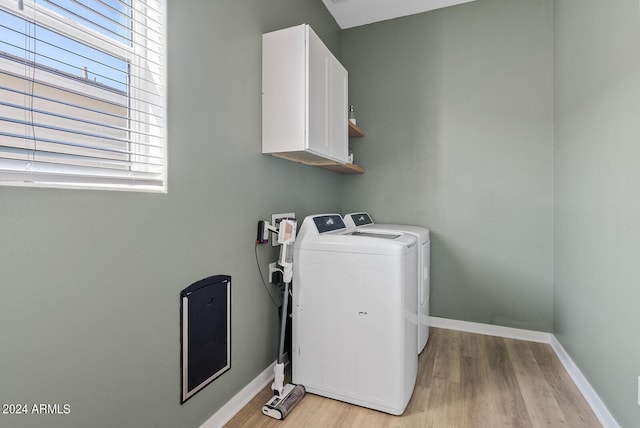 laundry room with cabinets, separate washer and dryer, and light wood-type flooring