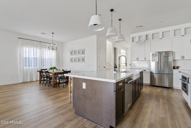 kitchen with a center island with sink, hanging light fixtures, stainless steel appliances, and sink