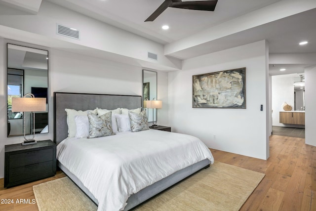 bedroom with connected bathroom, light wood-type flooring, and ceiling fan