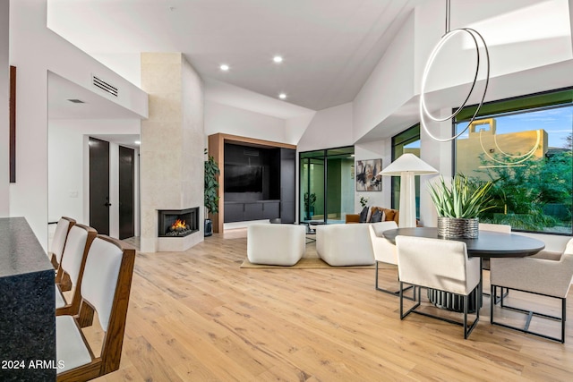 dining area featuring a high end fireplace, high vaulted ceiling, and light wood-type flooring