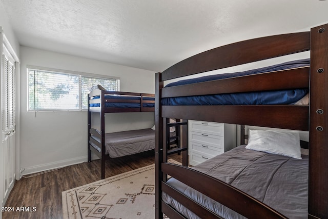 bedroom featuring a closet, dark hardwood / wood-style floors, and a textured ceiling