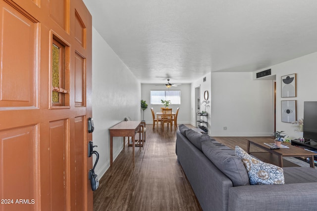 living room featuring ceiling fan, a textured ceiling, and dark hardwood / wood-style floors