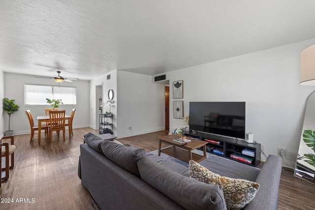 living room featuring a textured ceiling, dark wood-type flooring, and ceiling fan