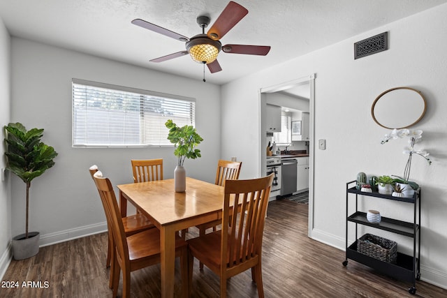 dining room with sink, ceiling fan, a textured ceiling, and dark hardwood / wood-style flooring