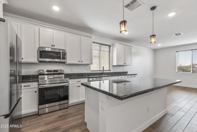 kitchen with stainless steel appliances, wood tiled floor, a sink, and plenty of natural light