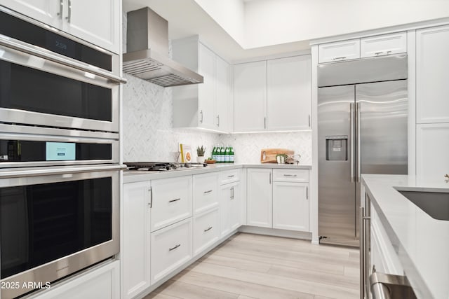 5250 E Deer Valley Dr Unit 140, Phoenix, AZ 85054 - kitchen featuring wall chimney exhaust hood, appliances with stainless steel finishes, light countertops, and white cabinetry