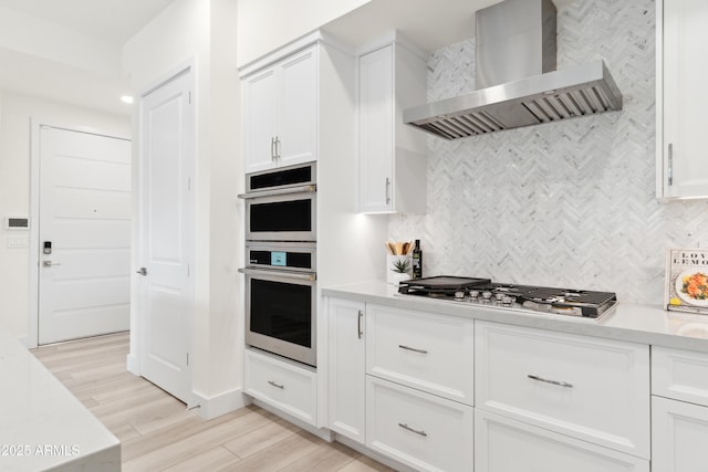 5250 E Deer Valley Dr Unit 140, Phoenix, AZ 85054 - kitchen featuring wall chimney range hood, appliances with stainless steel finishes, light countertops, tasteful backsplash, and light wood-style flooring