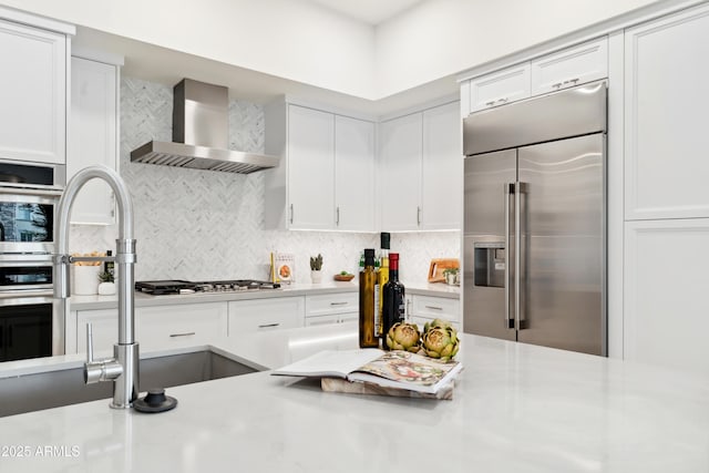 5250 E Deer Valley Dr Unit 140, Phoenix, AZ 85054 - kitchen with appliances with stainless steel finishes, wall chimney exhaust hood, light countertops, white cabinetry, and backsplash