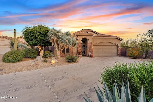 mediterranean / spanish home featuring fence, stucco siding, a tiled roof, concrete driveway, and an attached garage