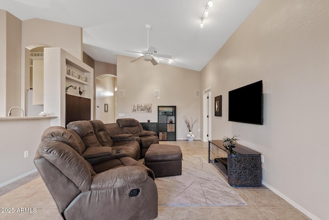 living area with arched walkways, ceiling fan, and light tile patterned floors
