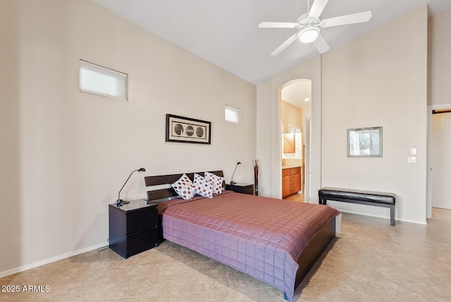 bedroom featuring arched walkways, baseboards, vaulted ceiling, and ensuite bath
