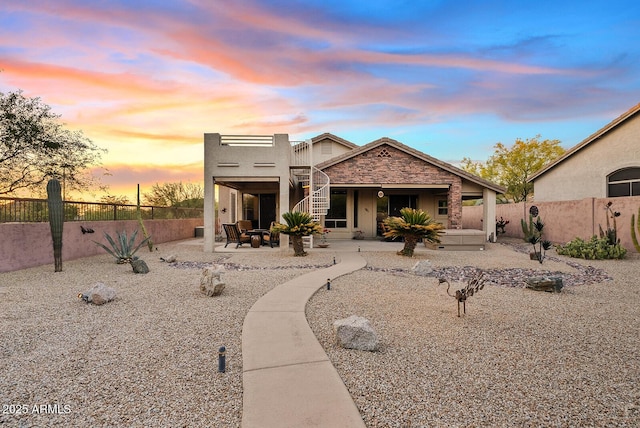 back of property featuring a patio, a fenced backyard, stucco siding, and stairs