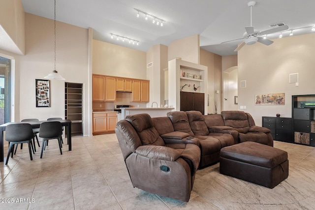 living room featuring a ceiling fan, visible vents, arched walkways, rail lighting, and high vaulted ceiling