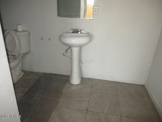 bathroom with a sink, tile patterned flooring, toilet, and baseboards