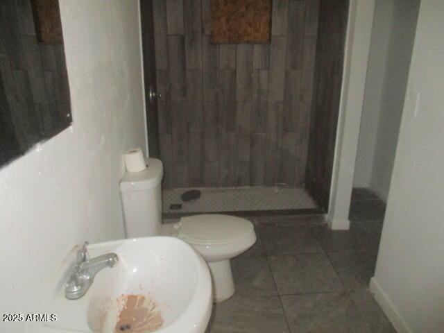 full bath featuring a stall shower, a sink, toilet, and tile patterned floors