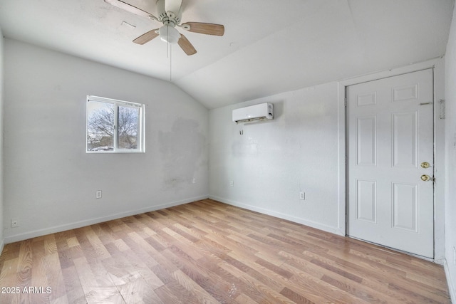 spare room featuring baseboards, a wall unit AC, lofted ceiling, ceiling fan, and light wood-type flooring