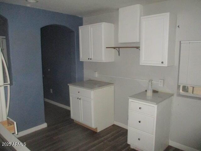 kitchen featuring dark wood-type flooring, white cabinetry, and baseboards