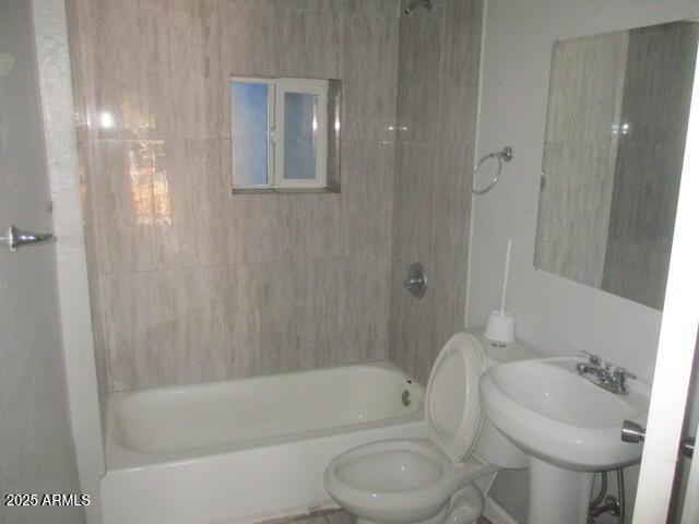 bathroom featuring toilet, shower / washtub combination, and a sink