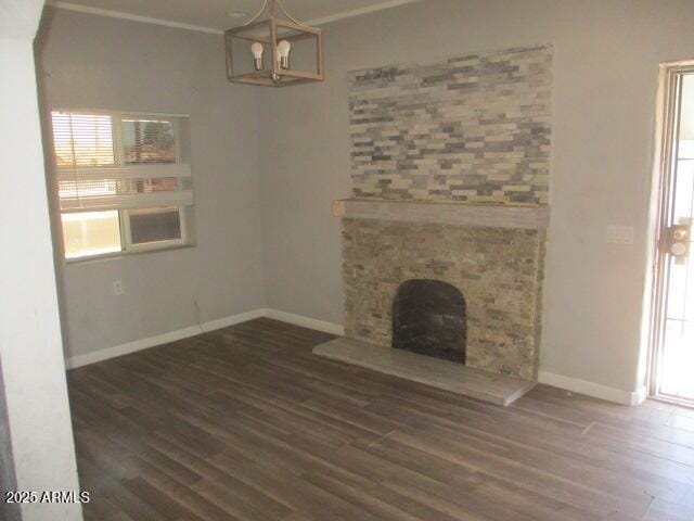 unfurnished living room with a fireplace with raised hearth, crown molding, baseboards, and wood finished floors