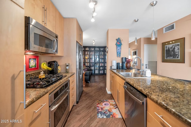 kitchen with sink, pendant lighting, appliances with stainless steel finishes, and dark stone counters