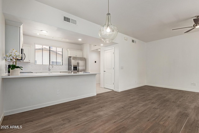 2315 N 52nd St Unit 144, Phoenix, AZ 85008 - kitchen featuring appliances with stainless steel finishes, a peninsula, light countertops, dark wood-type flooring, and decorative backsplash