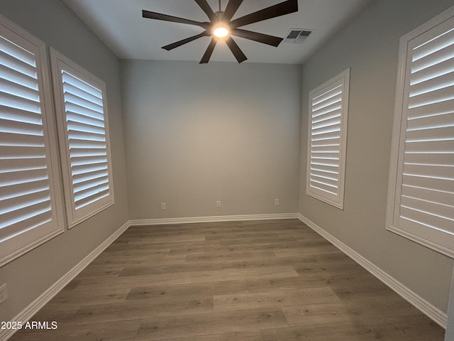 unfurnished room with a wealth of natural light, baseboards, and wood finished floors