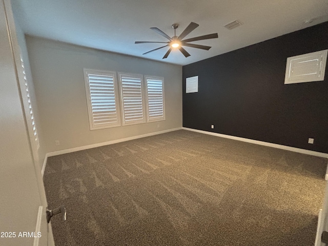 empty room featuring baseboards, visible vents, dark carpet, and ceiling fan